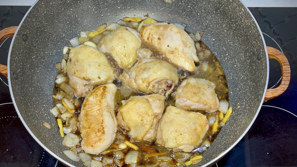 chicken, ginger, onion, garlic, soy sauce, vinegar, and water simmering in a pan