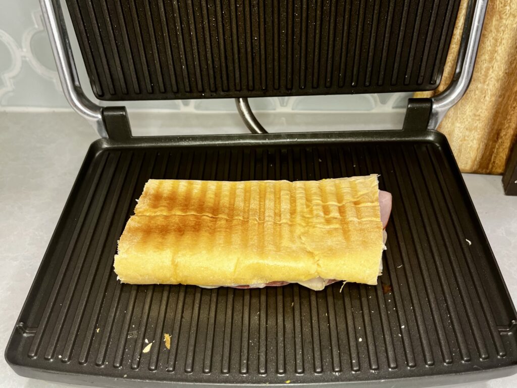 a cuban being pressed in a panini press 