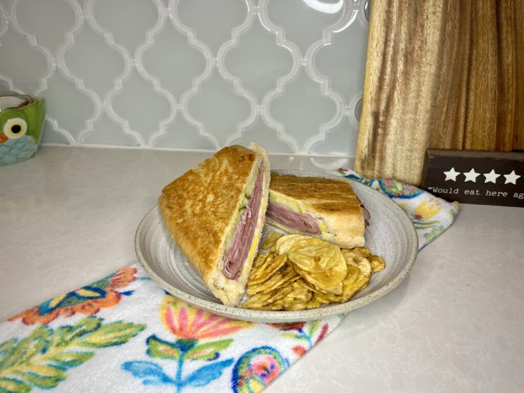 A pressed cuban sandwich on a plate with plantains