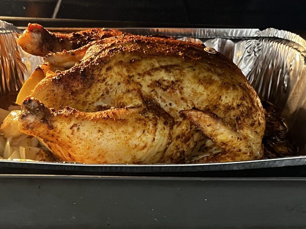 Cooked whole chicken in a roasting pan
