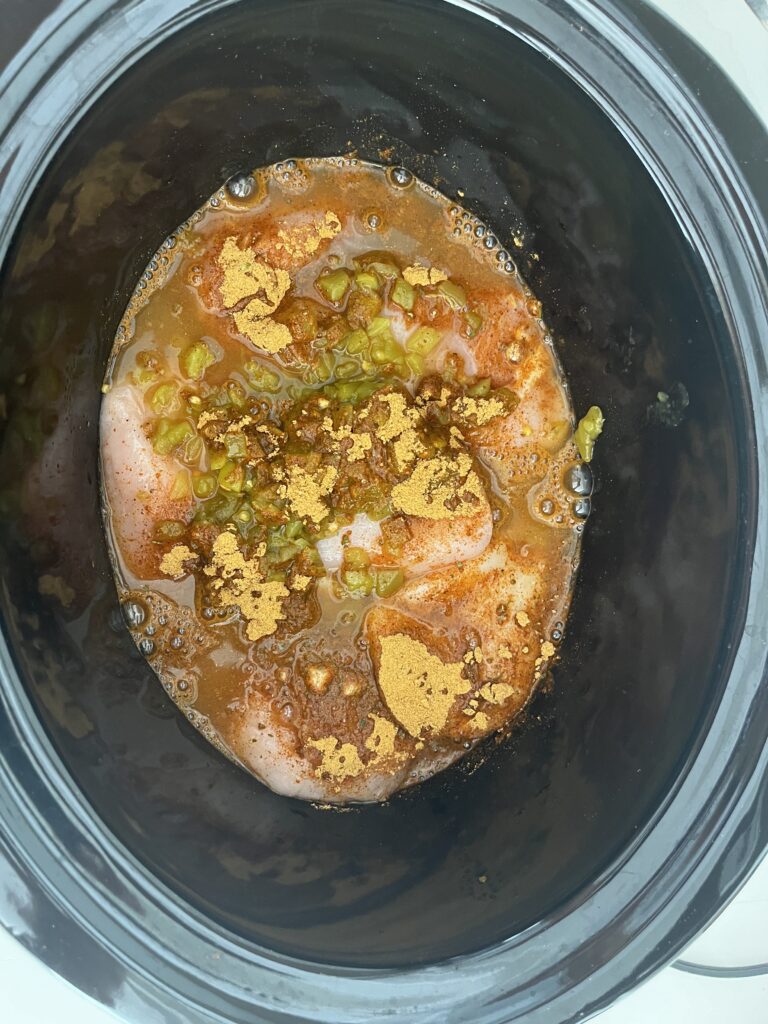 Chicken, diced chiles, taco seasoning and water in slow cooker
