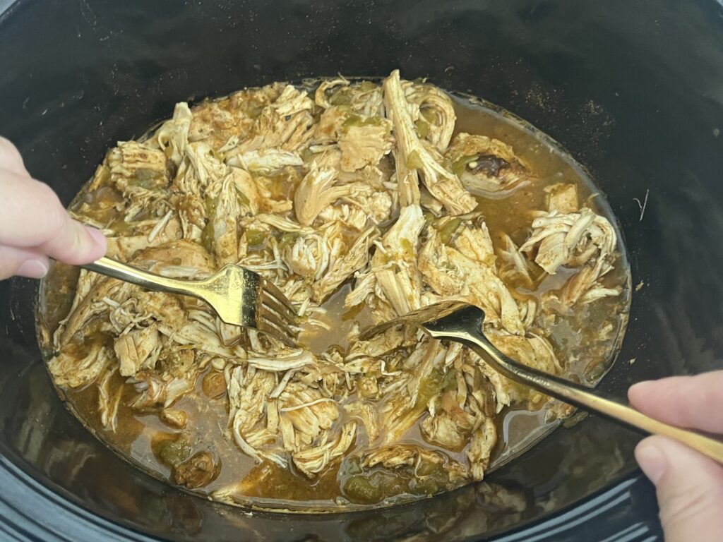 Using two forks to shred chicken in slow cooker
