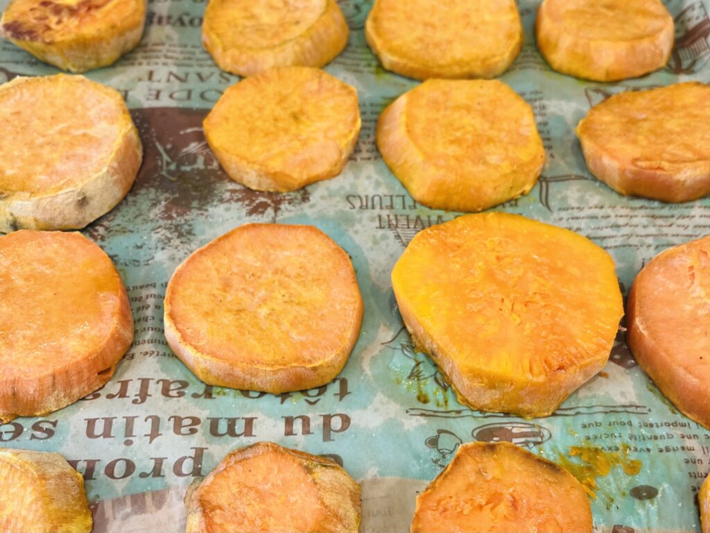 Baked sweet potatoes on lined baking sheet
