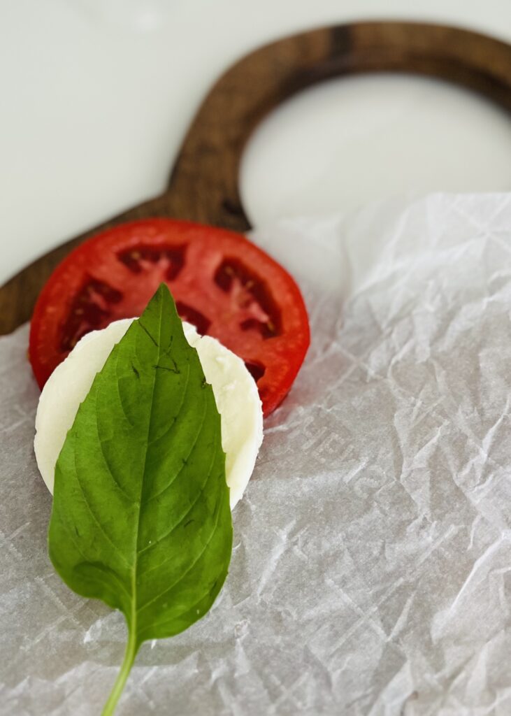 layered tomato, mozzarella cheese, basil on parchment paper