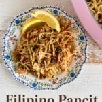 Delicious Filipino Pancit with shredded chicken, vegetables, and noodles served with lemon wedges on a decorative plate. Perfect for family meals and celebrations.