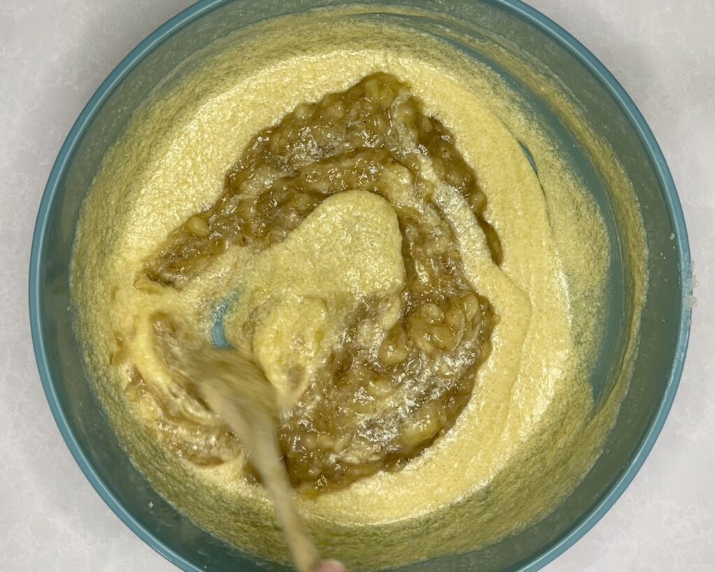 mashed bananas being stirred into bowl