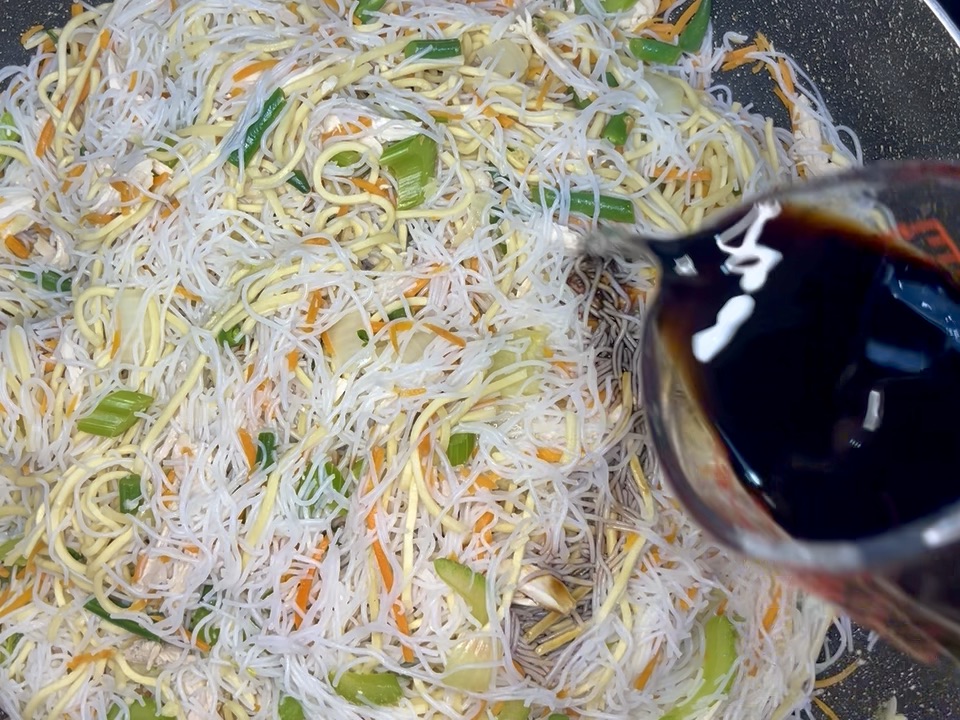 soy sauce being added to noodles