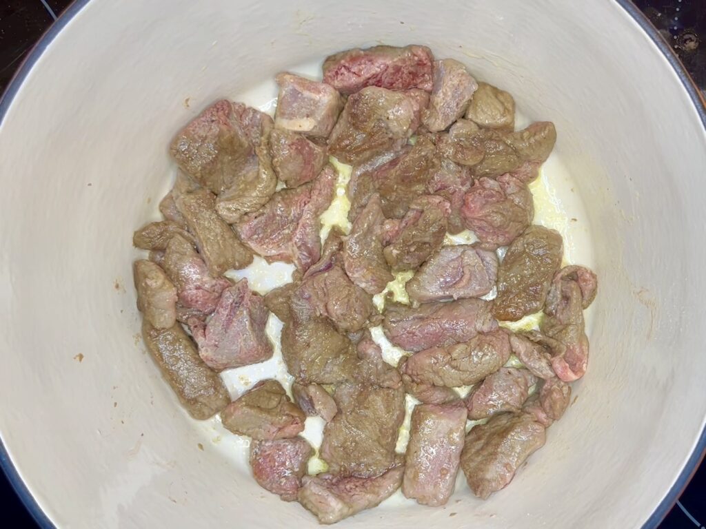 floured beef in a pot with oil and butter