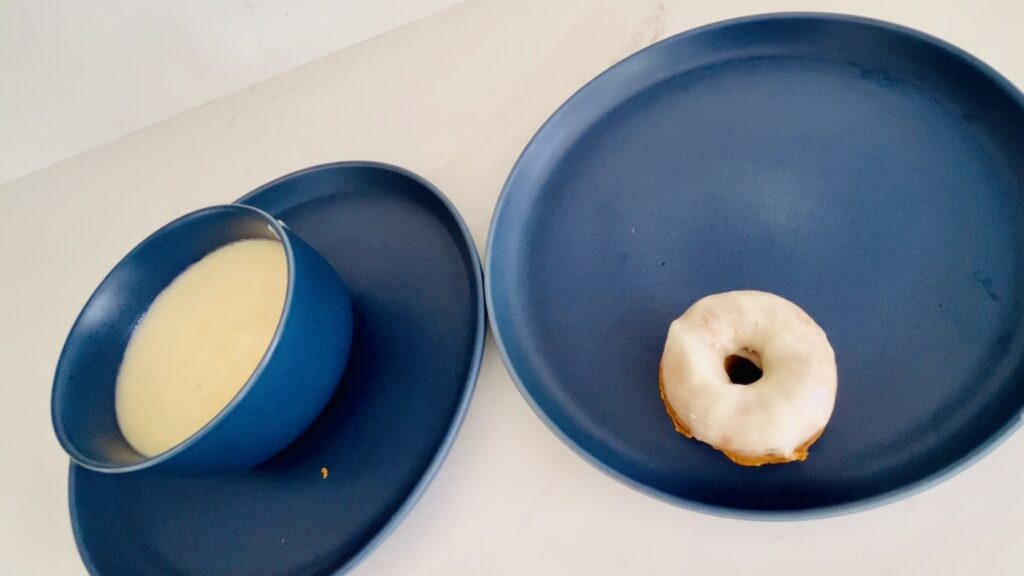 Donut dipped in cream cheese icing on a plate