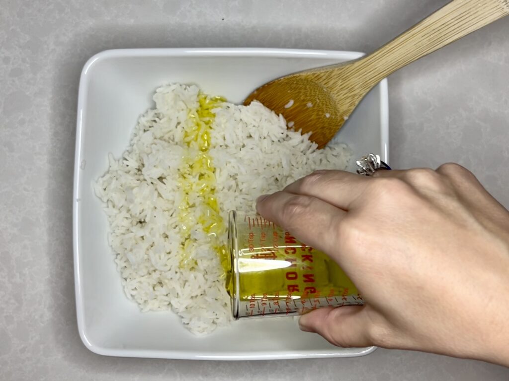 spanish olive oil being drizzled over top of rice in a bowl