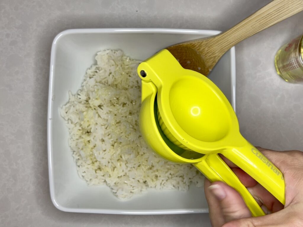 half of a lime being squeezed with a juicer over rice