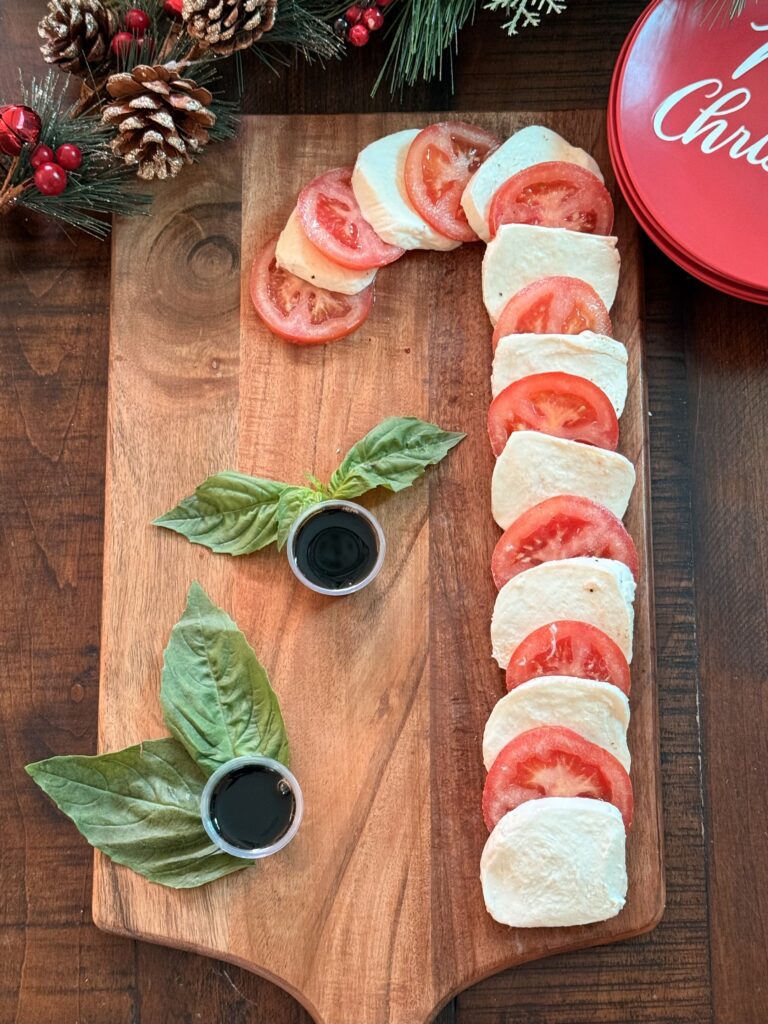 Caprese Salad ingredients in the shape of a Candy cane shape on a brown cutting board on the dining room table.