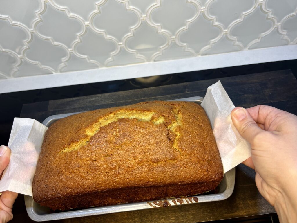 baked banana bread being removed from loaf pan