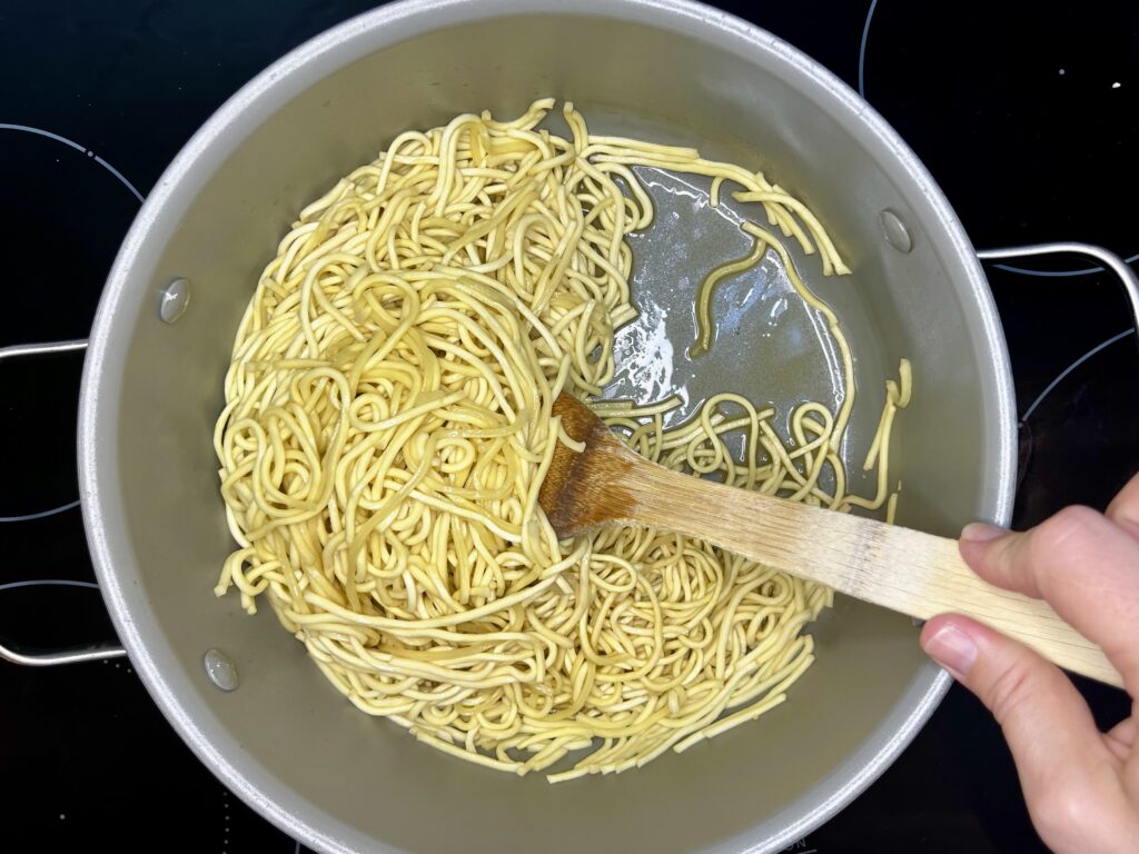 soft pancit canton noodles in a pot with chicken broth absorbed