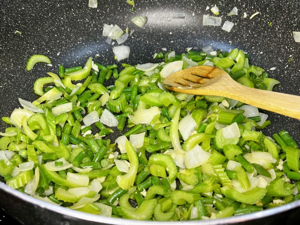 celery and green beans in a pot with garlic and onion