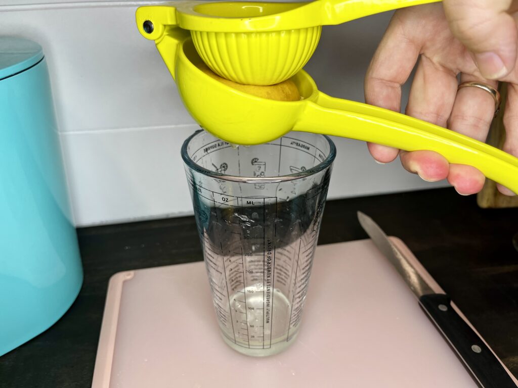 a lemon being squeezed over a glass