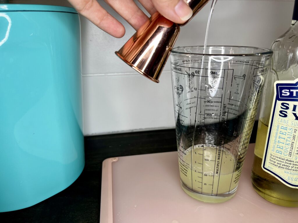 cocktail ingredients being measured and poured