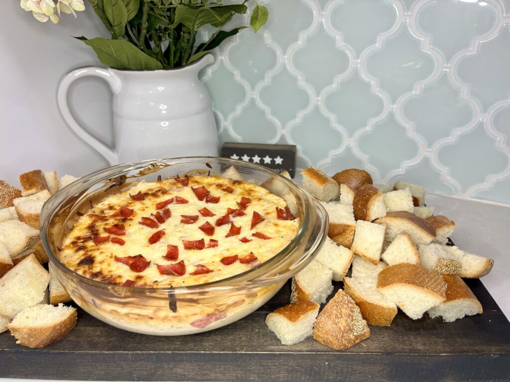 Baked pizza dip on a cutting board with cut French bread