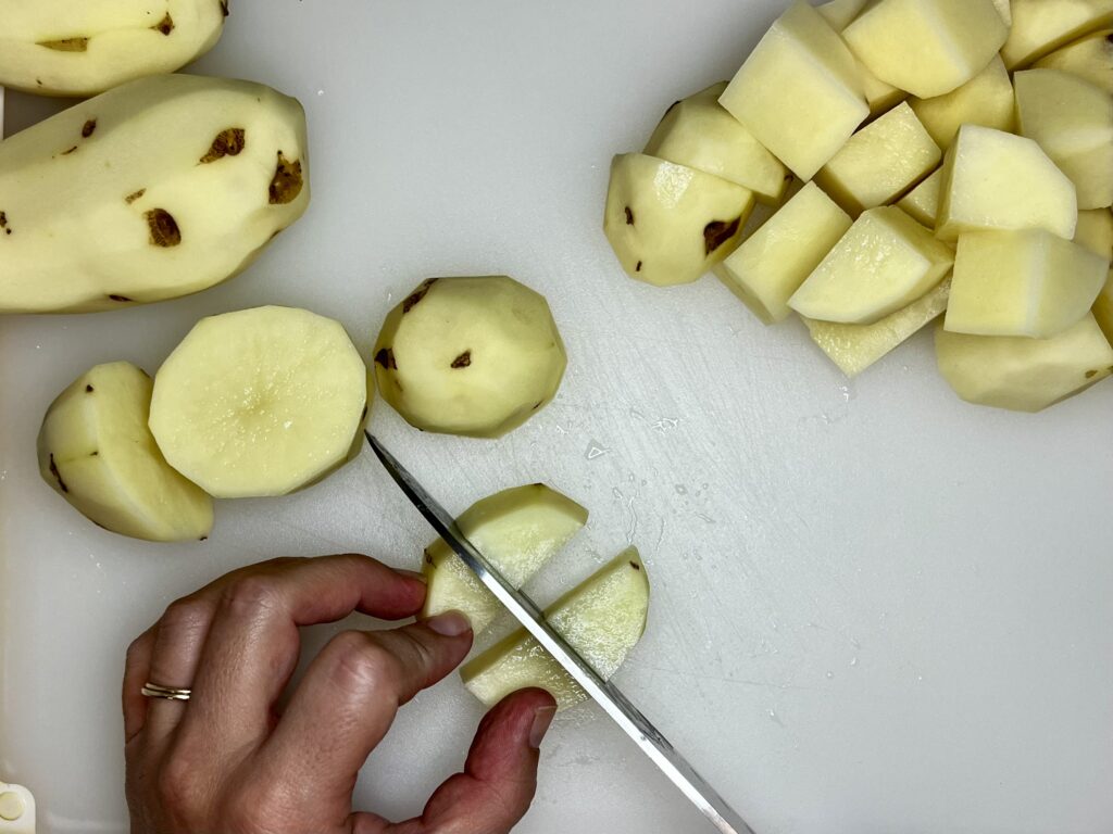 potatoes being cut into chunks