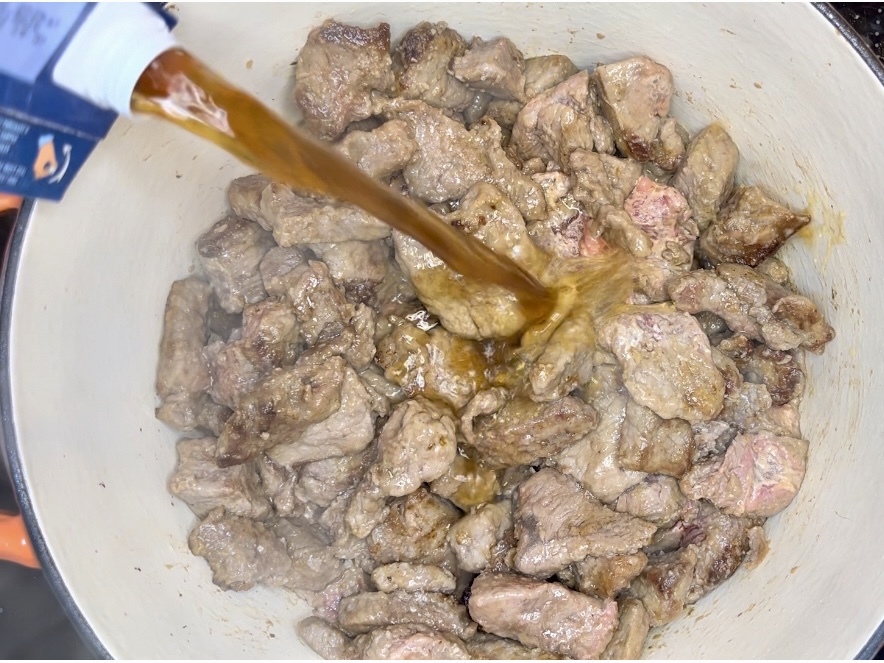 beef broth being poured into pot with beef