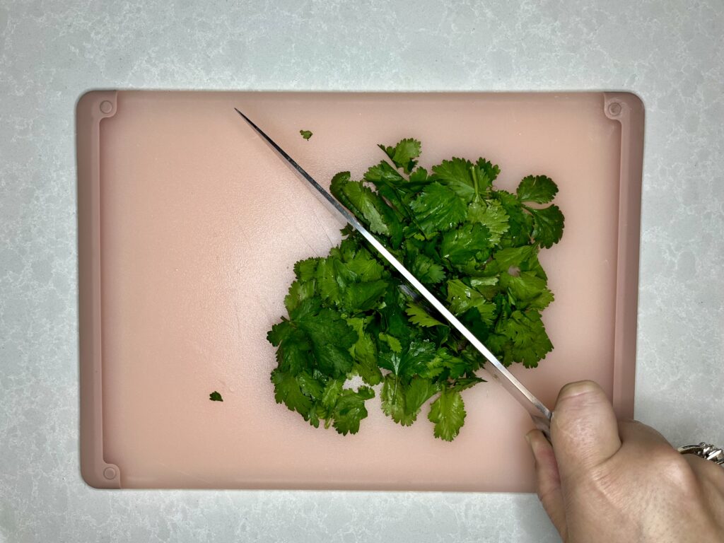 cilantro leaves being coarsely chopped with a chef's knife