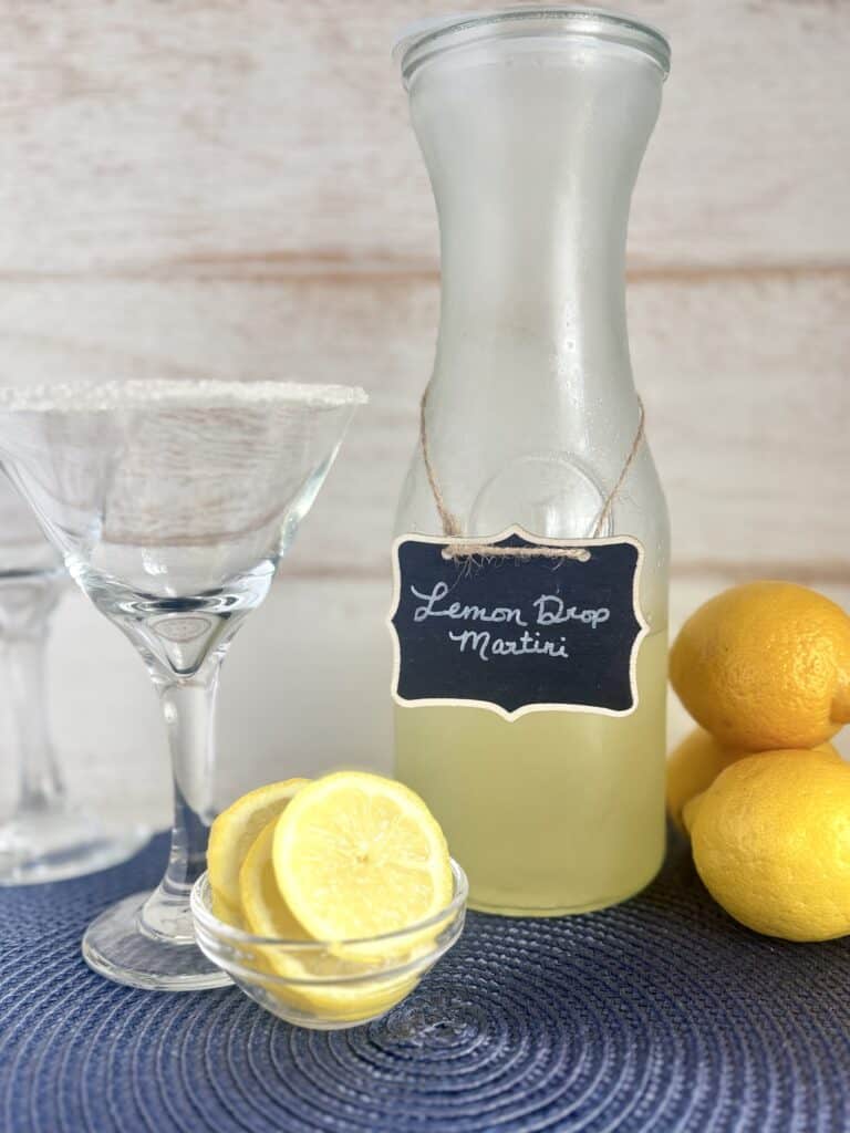 Refreshing Lemon Drop Martini in a glass with fresh lemons and a bottle labeled "Lemon Drop Martini" for easy cocktail recipe.