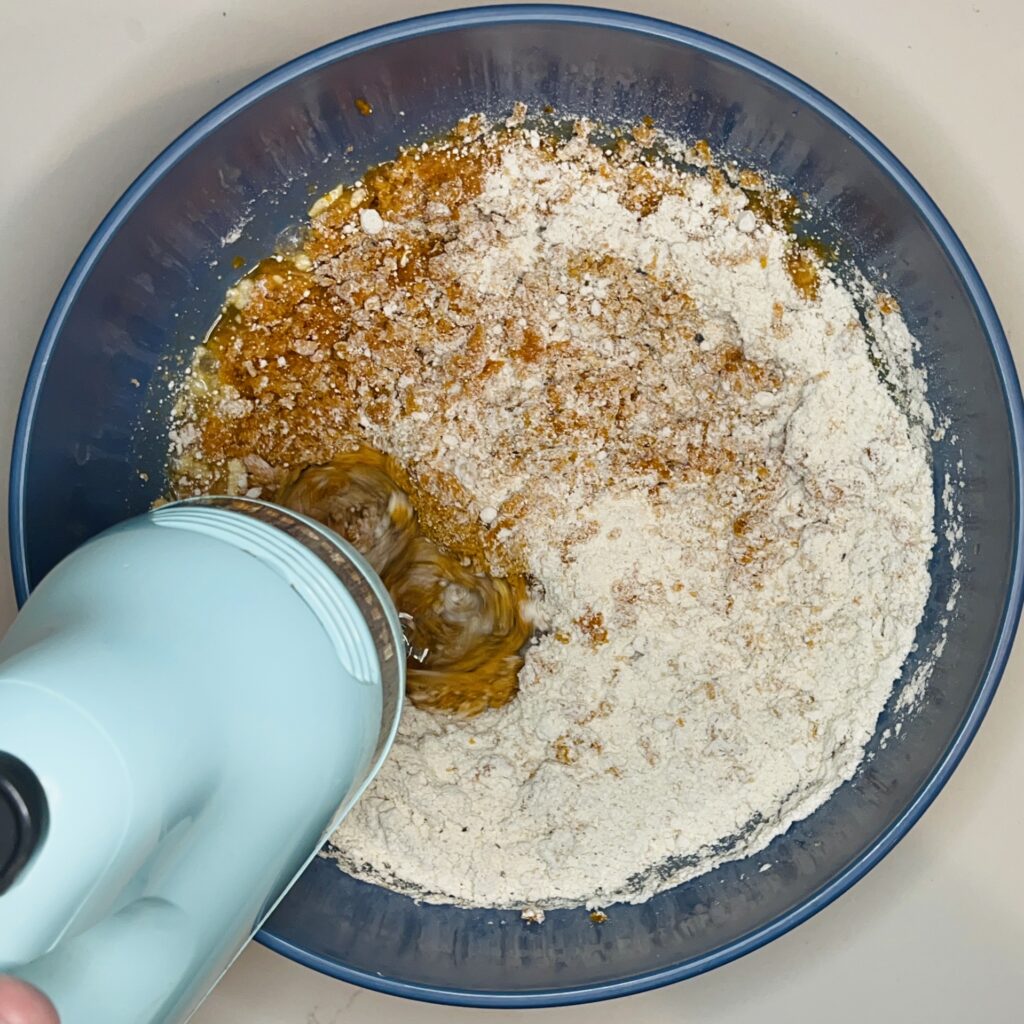 using am electric hand mixer mix ingredients in a large mixing bowl