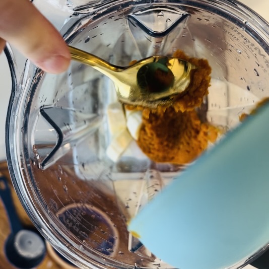 spooning pumpkin puree into a blender.
