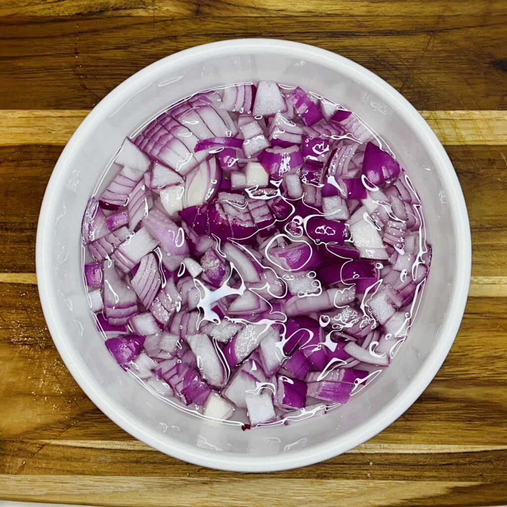 Diced red onion in a bowl of water.
