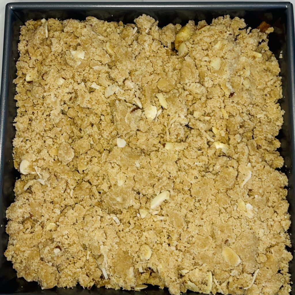 Fruit filling covered with crumble-ready to be baked in a baking pan
