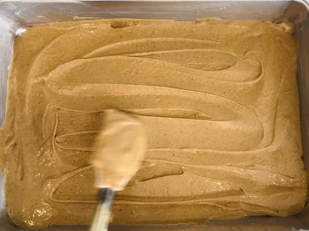 Smoothing the cake batter with a spatula in a rimmed baking sheet