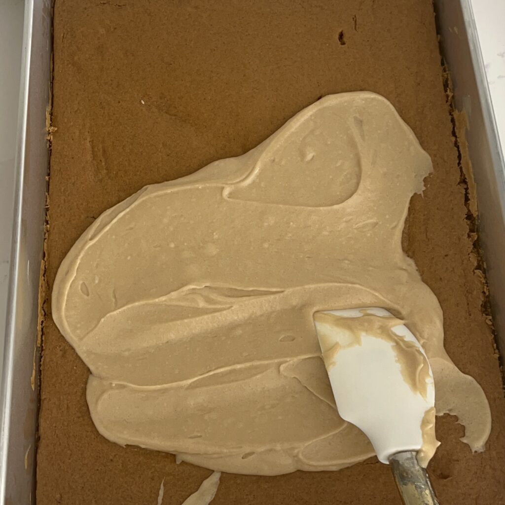 Icing being spread on cake in a rimmed baking sheet