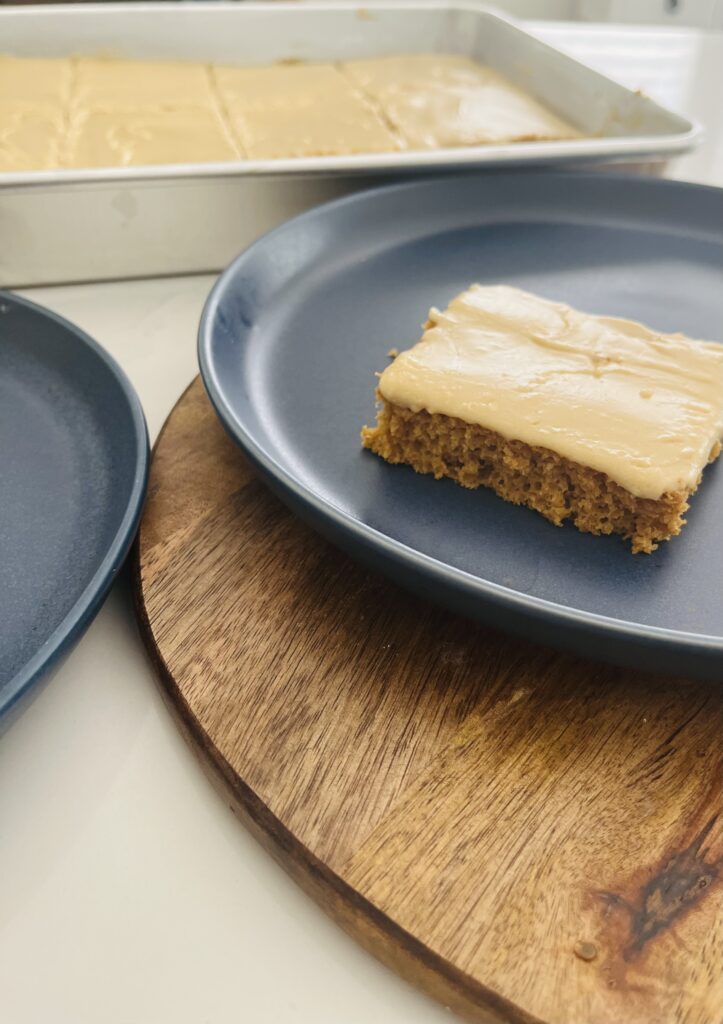 Pumpkin cake with brown sugar icing on a blue plate.