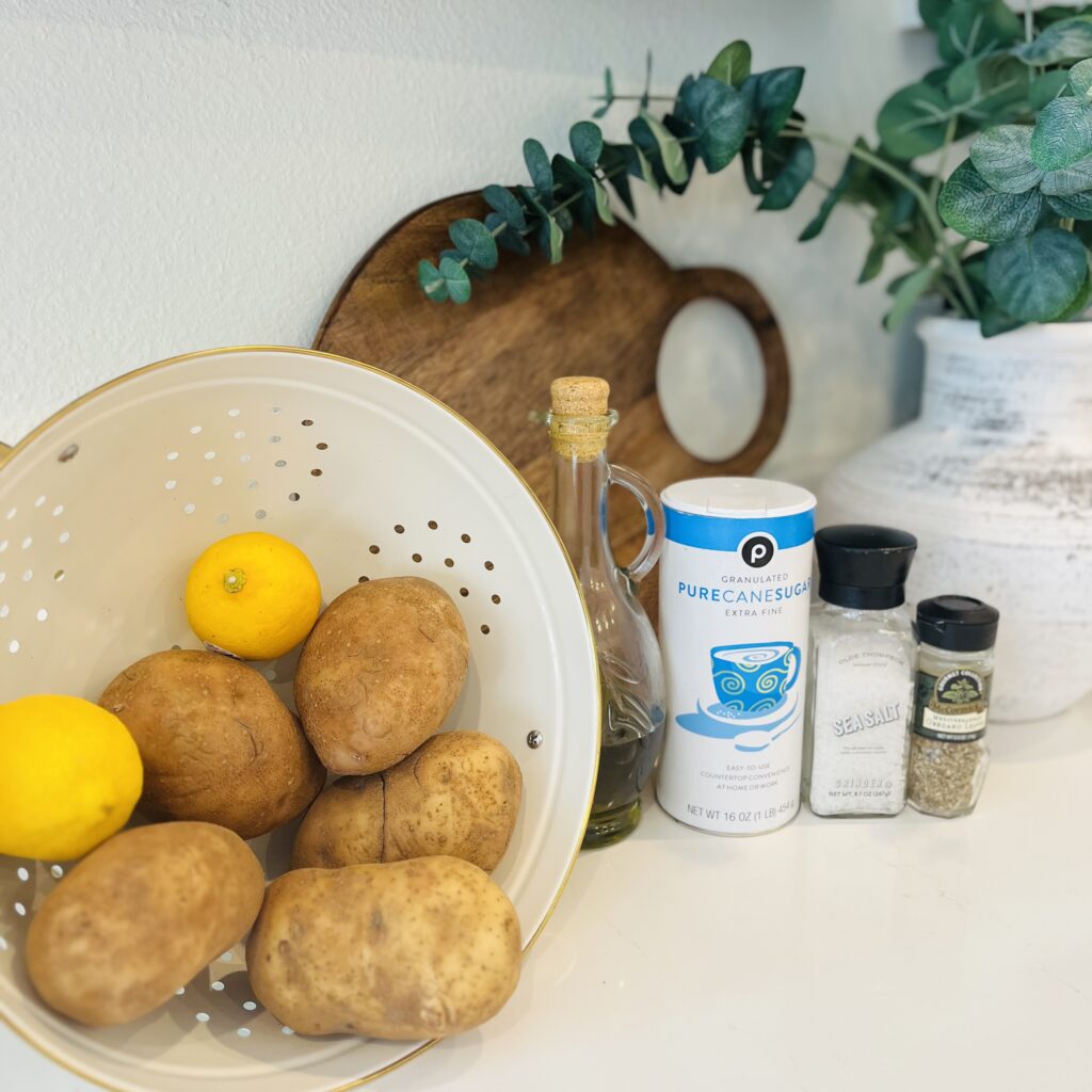 5 potatoes, 2 lemons, salt, sugar, olive oil, and dried herb seasoning on the counter
