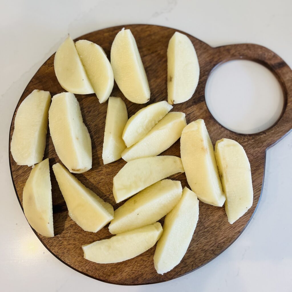 5 cut lengthwise and quartered potatoes on a cutting board