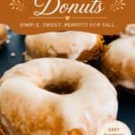 Pumpkin donuts with cream cheese icing on a dark surface, showcasing fall-inspired dessert with a sweet glaze.