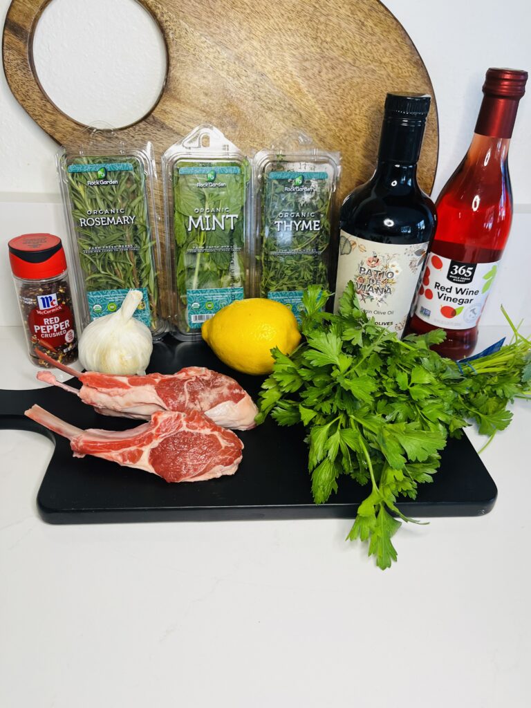 Double cut lamb chops, red wine vinegar, lemon, olive oil, parsley. red pepper flakes, garlic, fresh rosemary, thyme and mint on the counter
