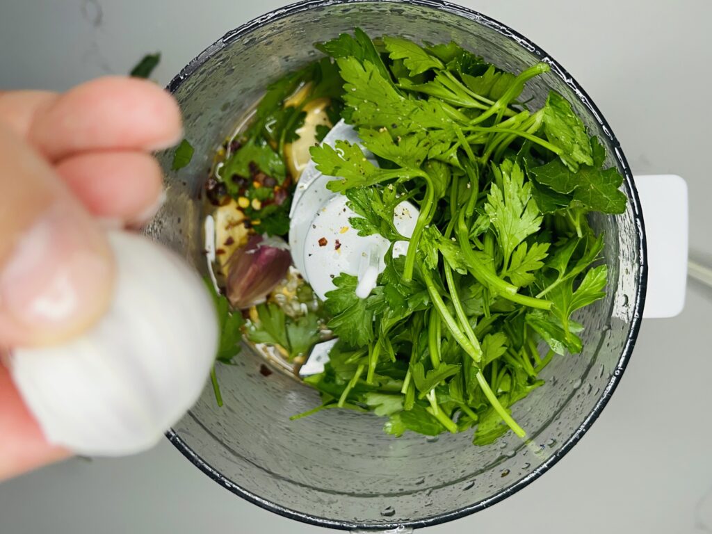 1/2 cup olive oil, 1 tsp red wine vinegar, 2 cup finely chopped parsley, 10 mint leaves, garlic cloves, dash of and red pepper flakes in a food processer

salt & pepper into a food processor picture 2.