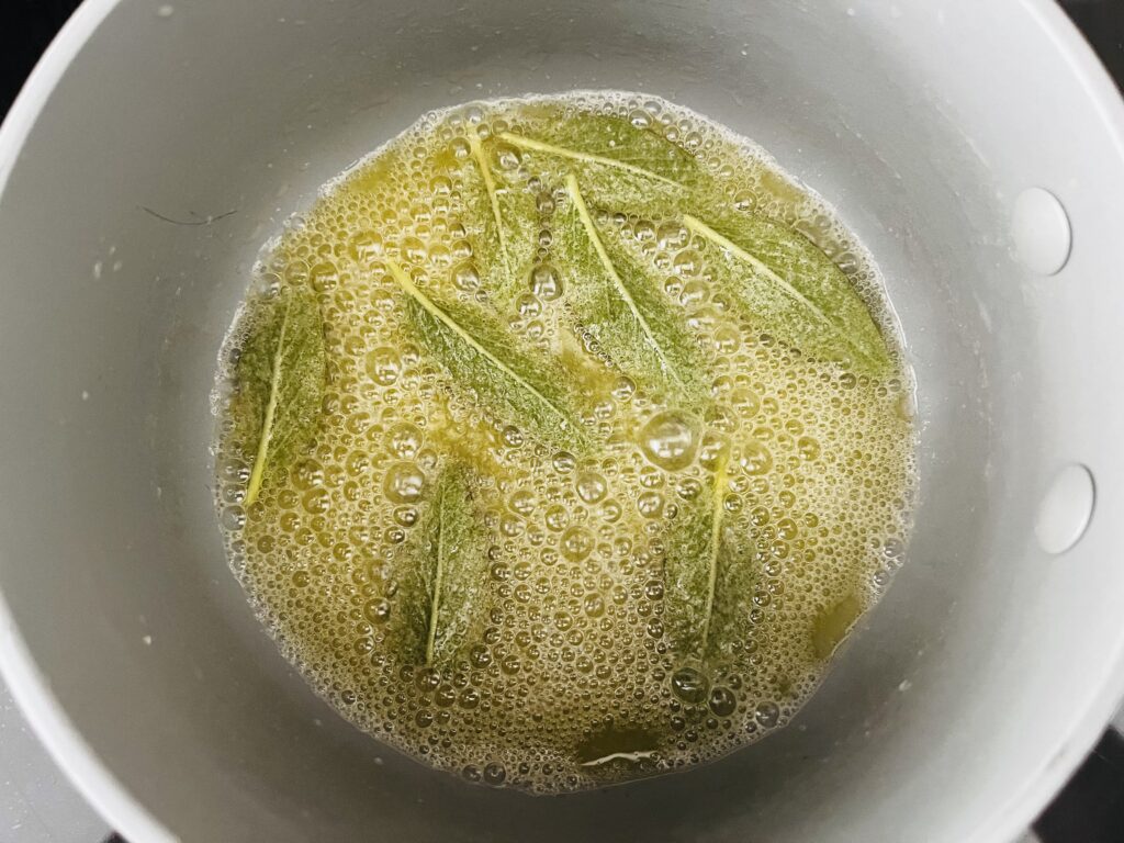 Crisp sage leaves in brown butter in a pot on the stove