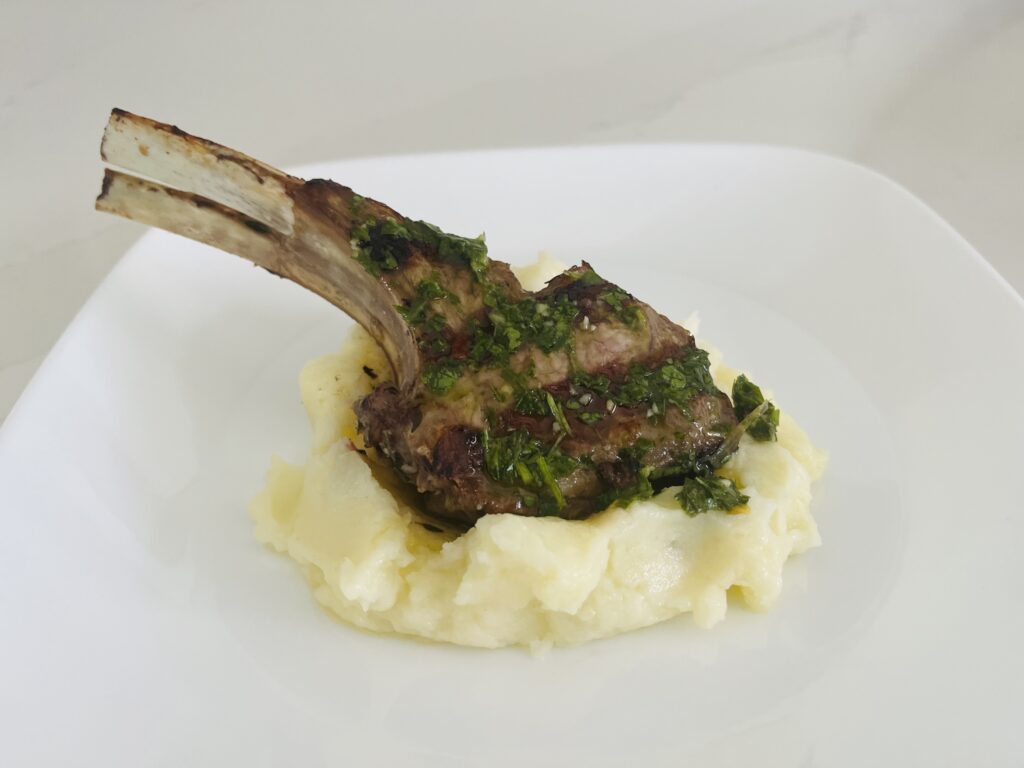 Double lamb chop with chimichurri sauce over brown butter and sage mash potatoes on a plate