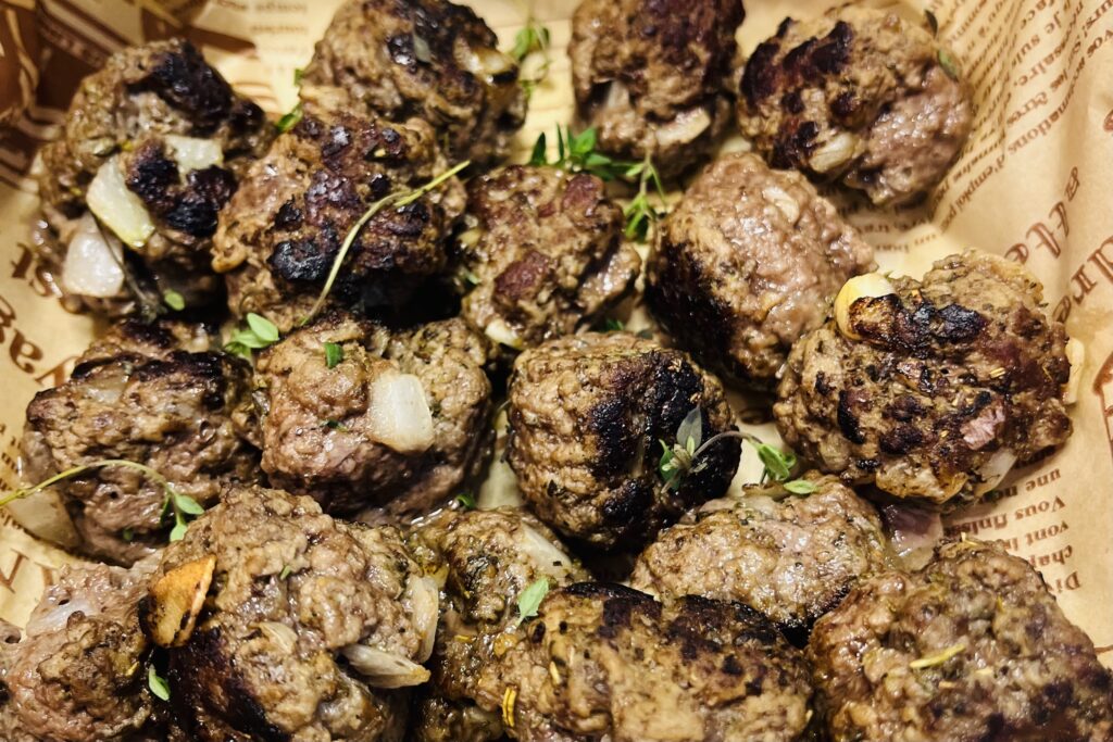 Done onion and garlic meatballs in a lined bowl.