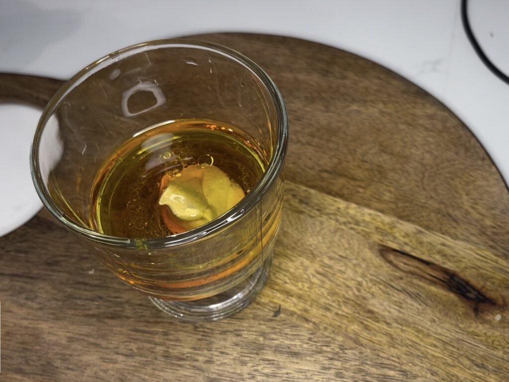 Adding dijon mustard to vinaigrette in glass bowl on the counter