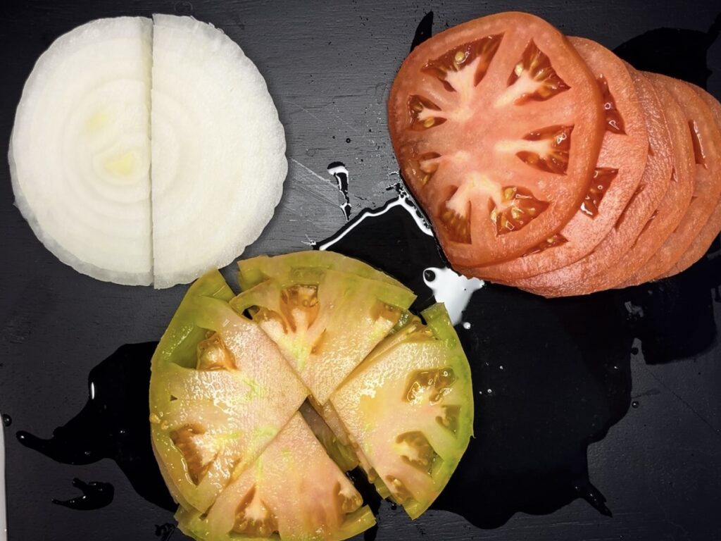 Cut onion in half cut tomatoes on a plate.
