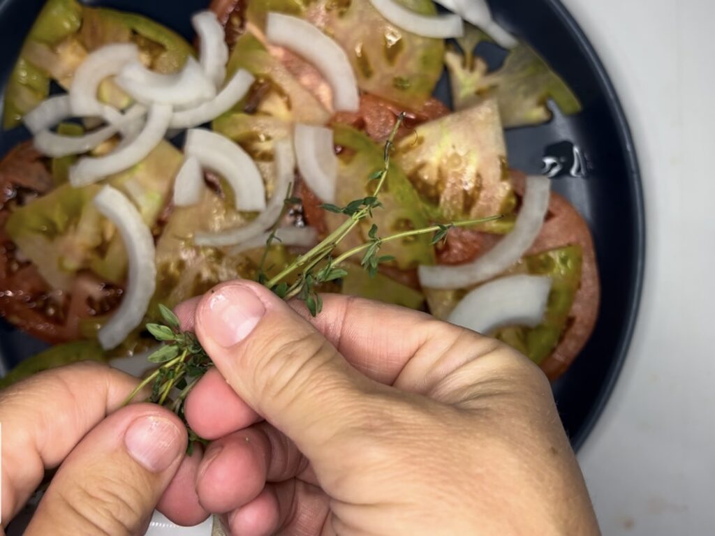 Sprinkled onions on top of plated tomatoes and fresh thyme.
