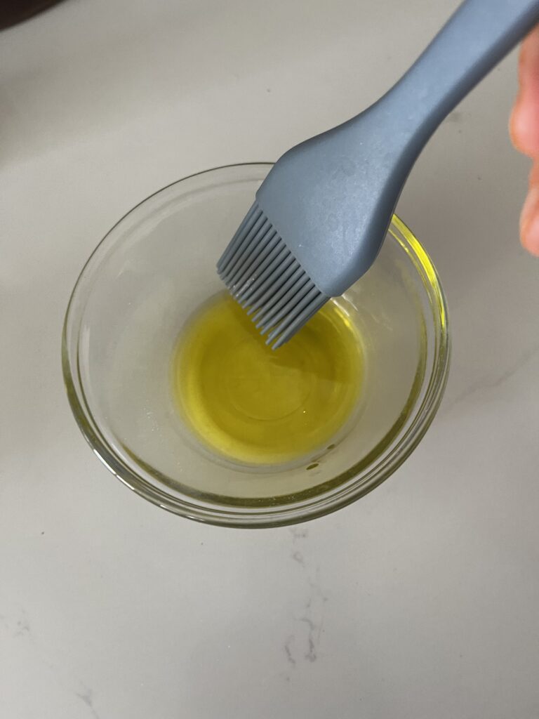 Basting brush dipped into olive oil on the counter