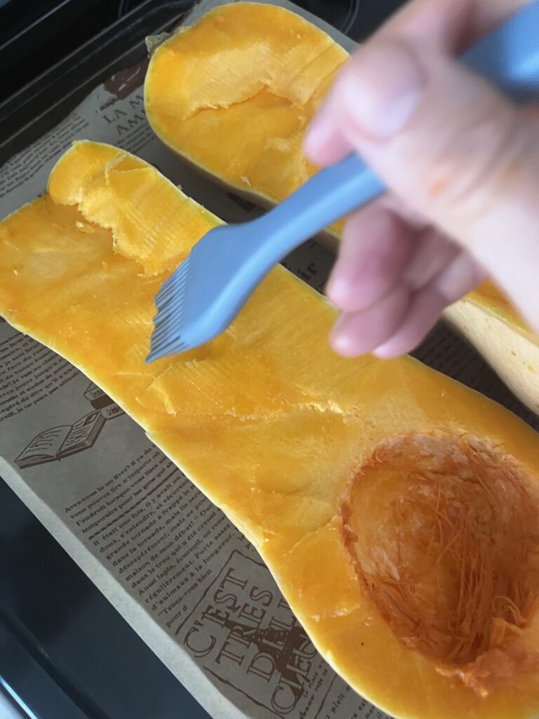 Basting olive oil onto the squash.
