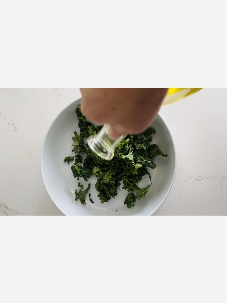 Pouring olive oil over kale in a bowl