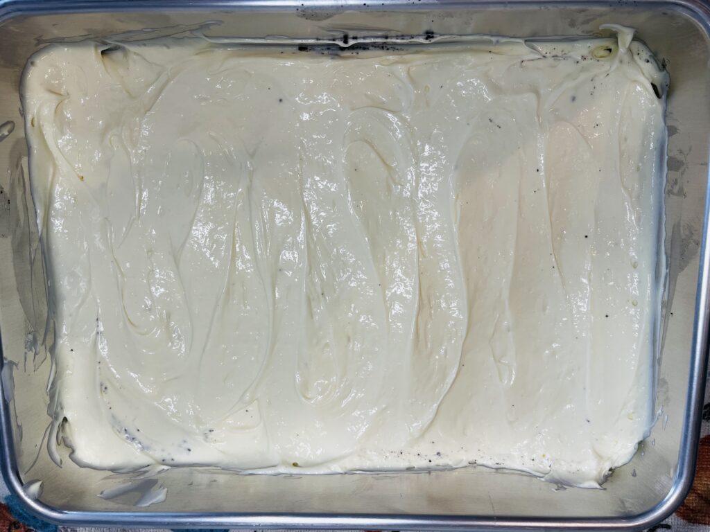 Cream cheese and cool whip layer on top of Oreo cookie in a baking sheet pan.