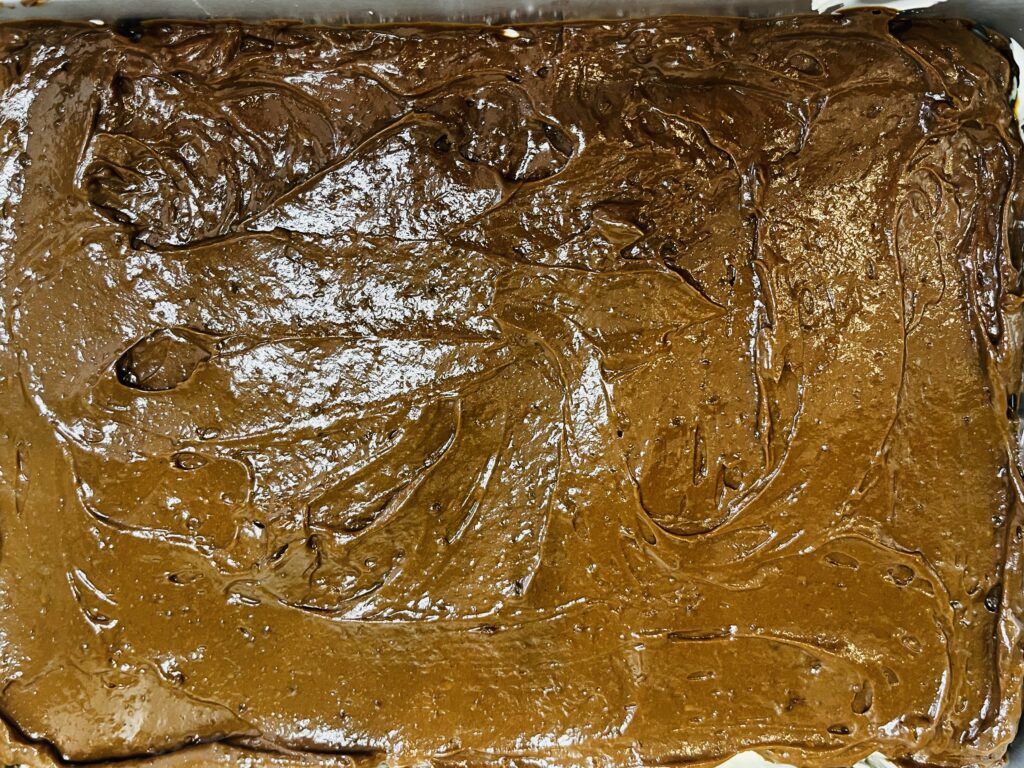 Chocolate pudding spread over cheesecake filling in a baking sheet pan
