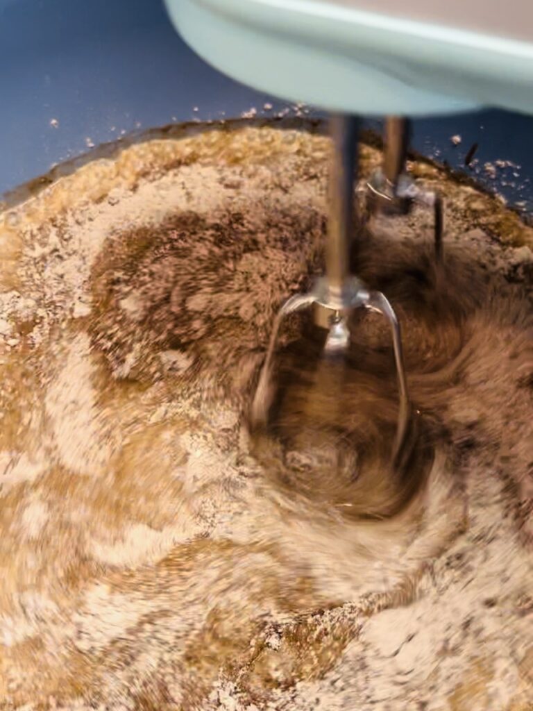 Mixing dry pudding mix with milk using an electric mixer
